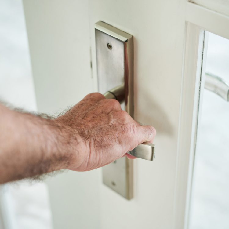 Crop shot of male hand opening metal handle of glass door